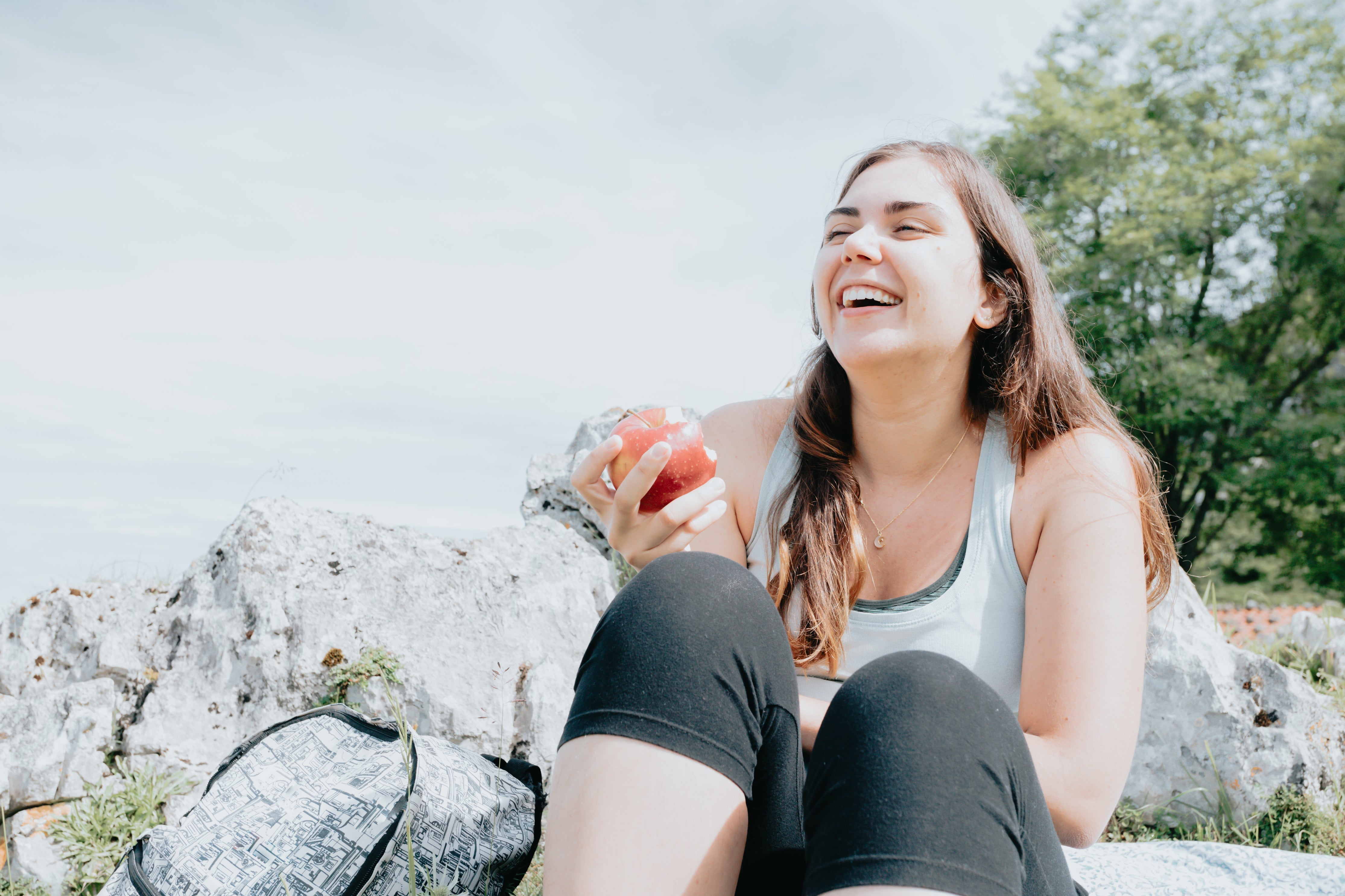 files/woman-laughs-while-sitting-outdoors-on-rocks.jpg